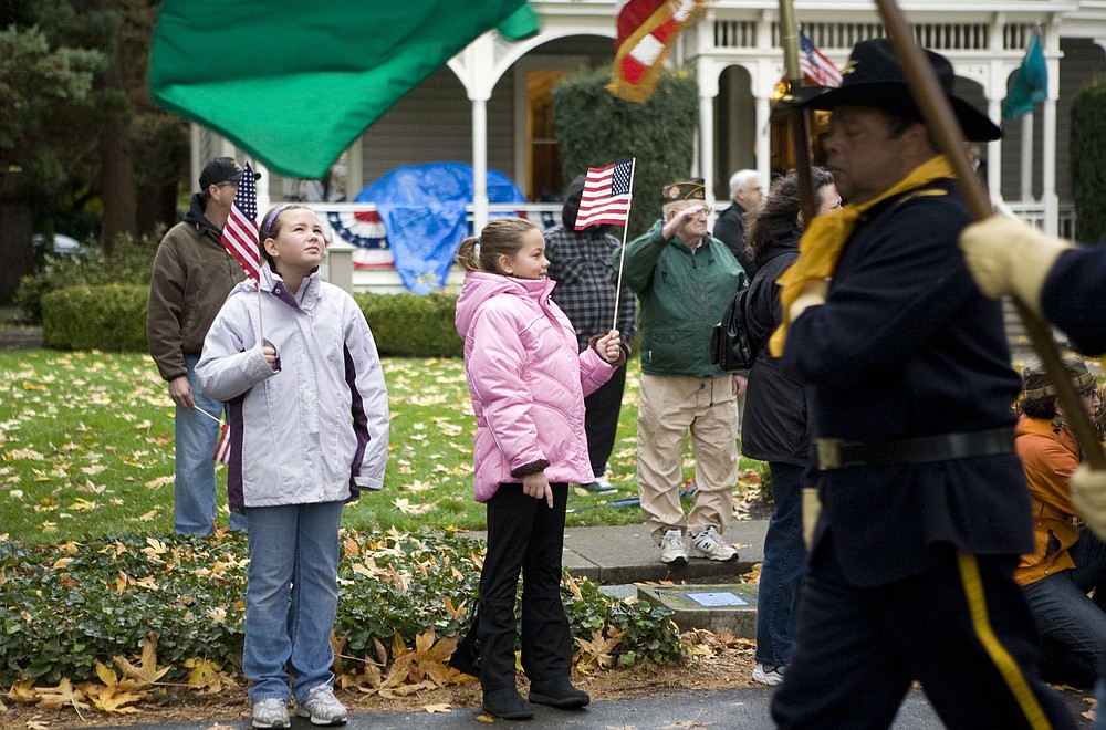 Photos by Vivian Johnson/ For The Columbian
	Two girls watch Saturday morning as the color guard carries American and Washington state flags during the 23rd annual Celebrate Freedom Veterans Parade. People of all ages braved the cold, wet weather to pay tribute to veterans and active-duty soldiers.