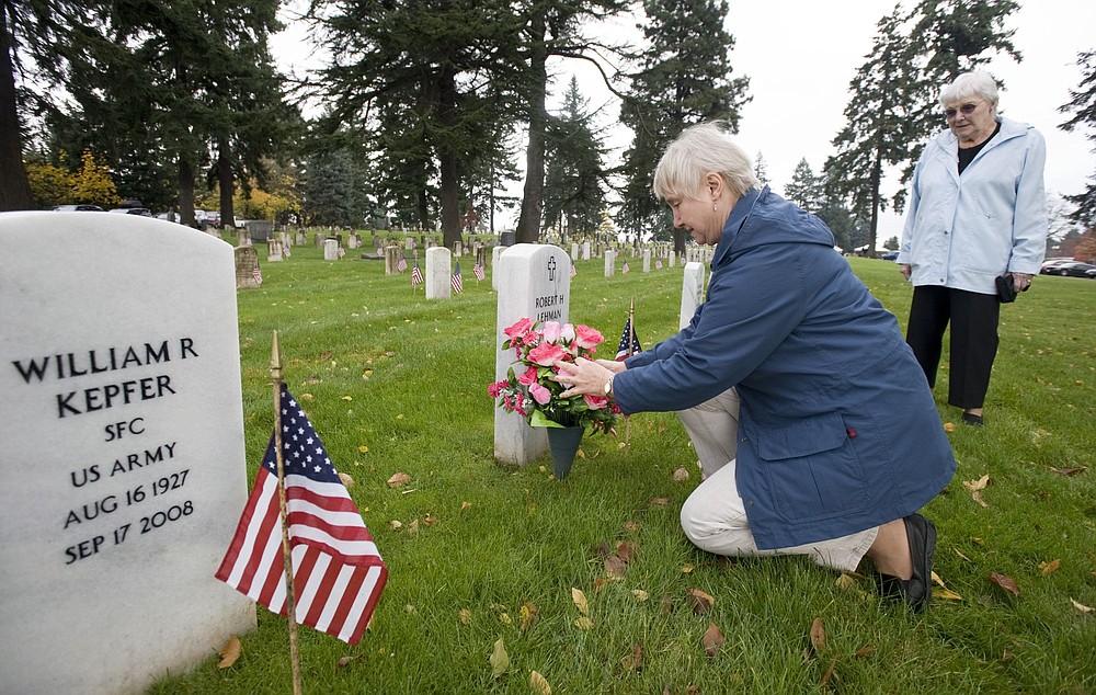 STEVEN LANE/The Columbian
Ruth Lehman places flowers on the grave of her father, World War II and Korean War veteran Robert Lehman, as her mother, Carolyn Lehman, watches Wednesday.