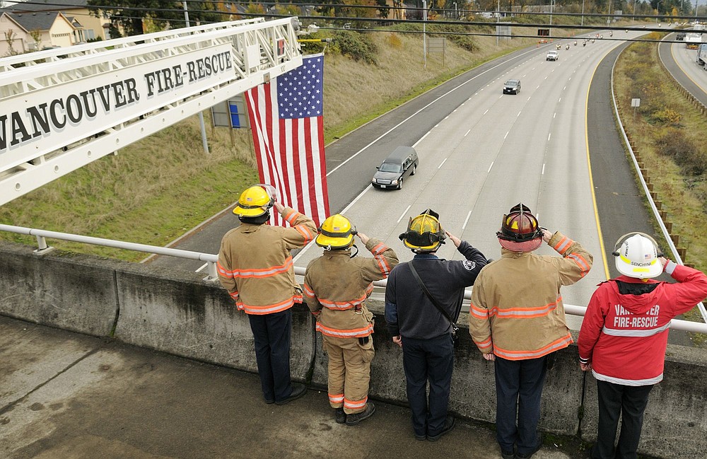 Troy Wayrynen/The Columbian
Vancouver Fire Department members Obie Bowman, left, Mike McHugh, John Windus, Tige Harmon and Mike Senchyna stand at attention and salute as the body of Army Pfc. Christopher Ian Walz comes home Thursday along Interstate 205.