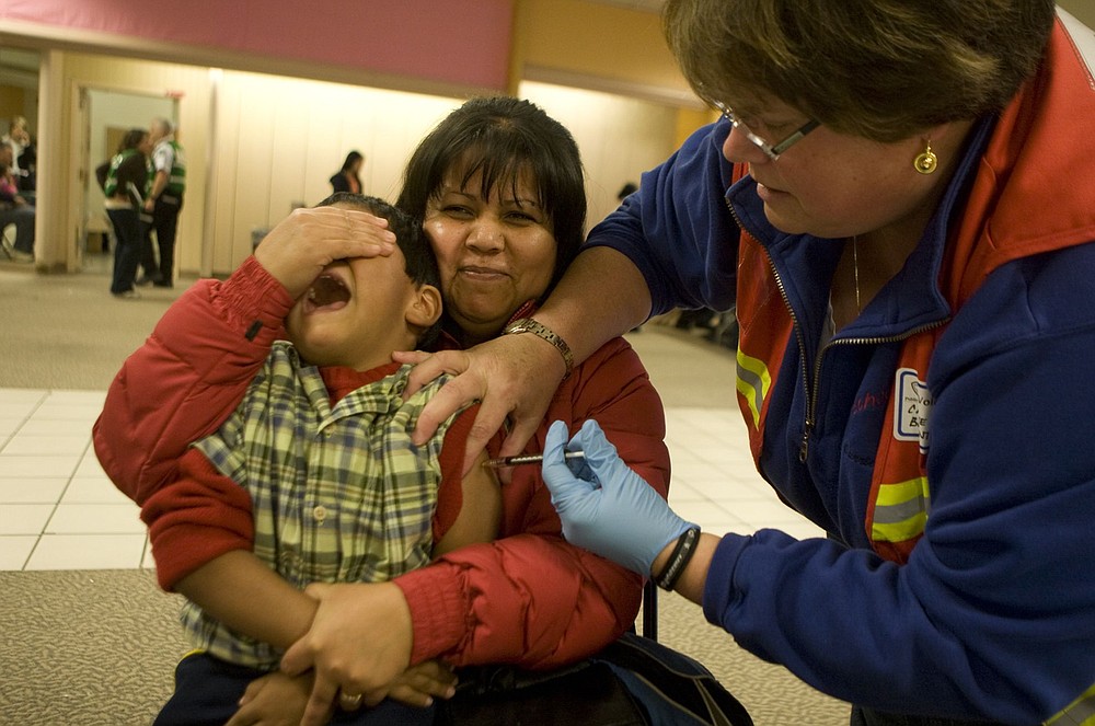 Rafaela Beltran covers the eyes of her son, Jose Manuel, so he can't see the needle while receiving his H1N1 vaccination during a county clinic at Vancouver Mall in 2011. One thousand people had already lined up for shots when the clinic opened at 11 a.m.; 5,000 doses were available.