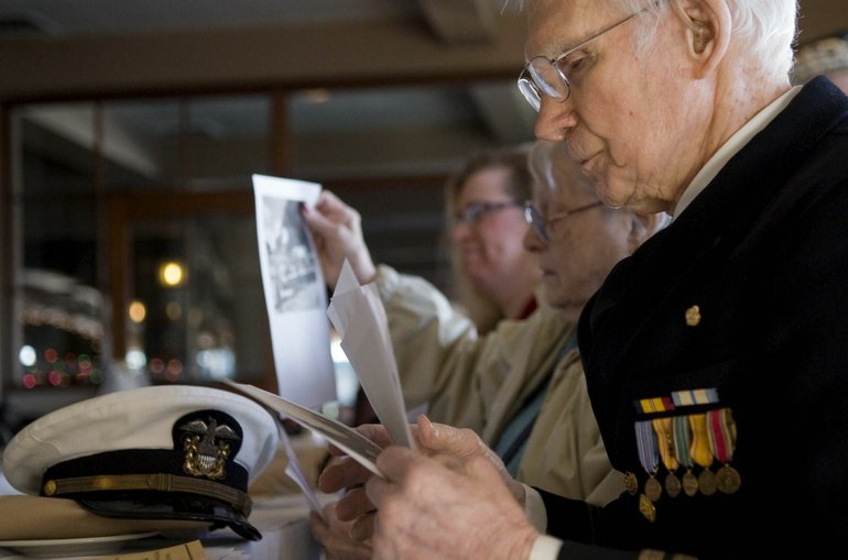 Zachary Kaufman/The Columbian
Pearl Harbor survivor Larry Lydon, from right, wife Bette Lydon and their granddaughter Anne Lydon-Beaton look through pictures of the attack on Pearl Harbor during Monday's memorial event at the Red Lion Inn at the Quay.