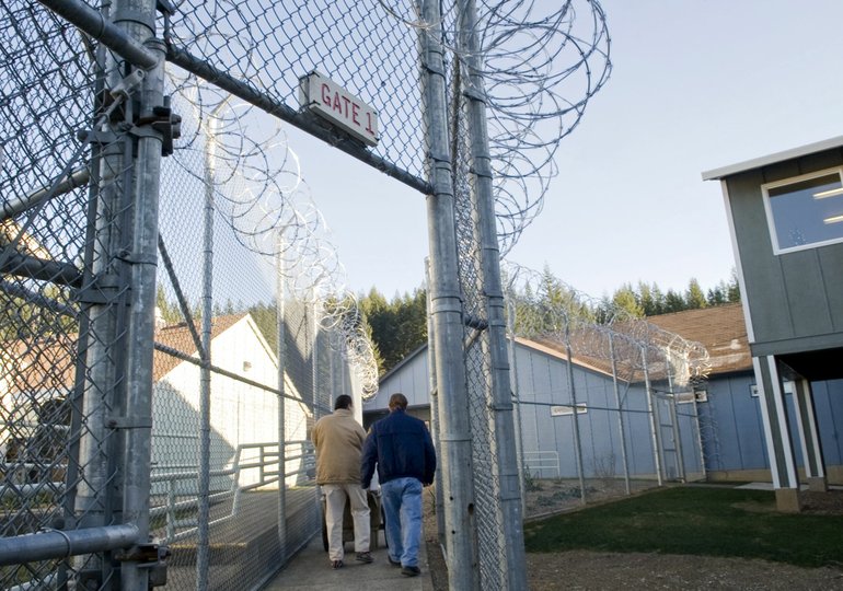 An inmate and guard walk through a gate at Larch Corrections Center in east Clark County.