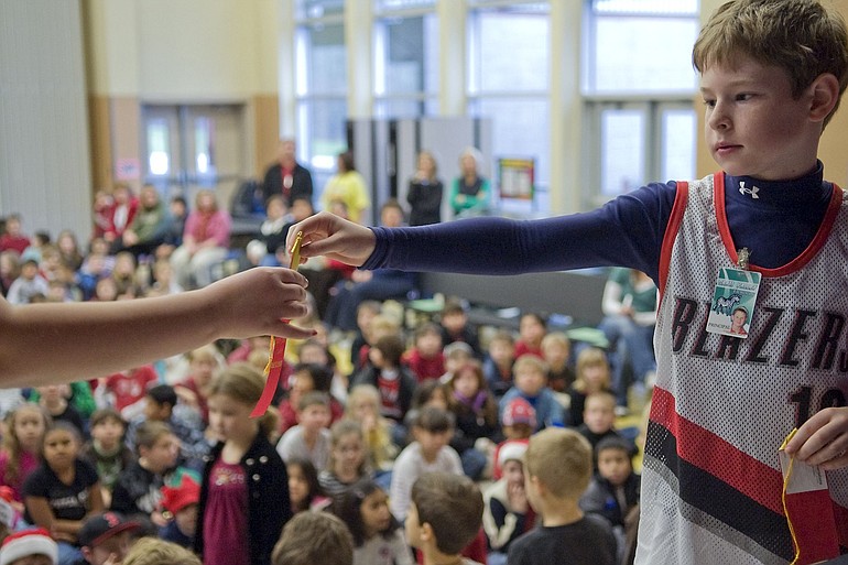 Third-grader Joey Przedwojewski hands out ribbons to students who participated in an art contest.