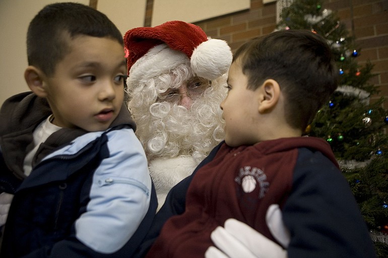Omar Salinas, 6, left, and his brother Uriel Salinas, 4, sit on Santa's lap and tell him what they want for Christmas on Thursday during Hazel Dell's annual free Christmas party for kids.