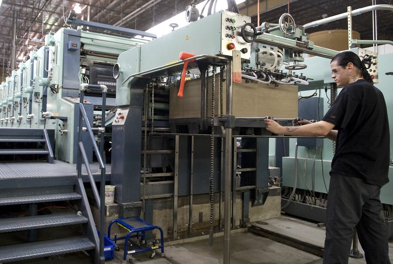 Second pressman Sean McElligott loads paper into a printing press at Rose City Printing &amp; Packaging Inc. in Vancouver.