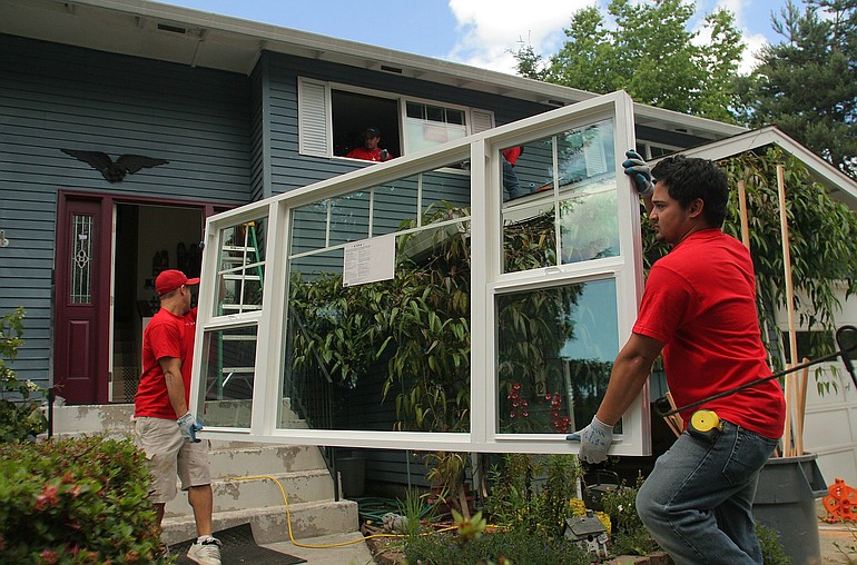 Workers with a Vancouver window company replace old windows with more energy-efficient ones.