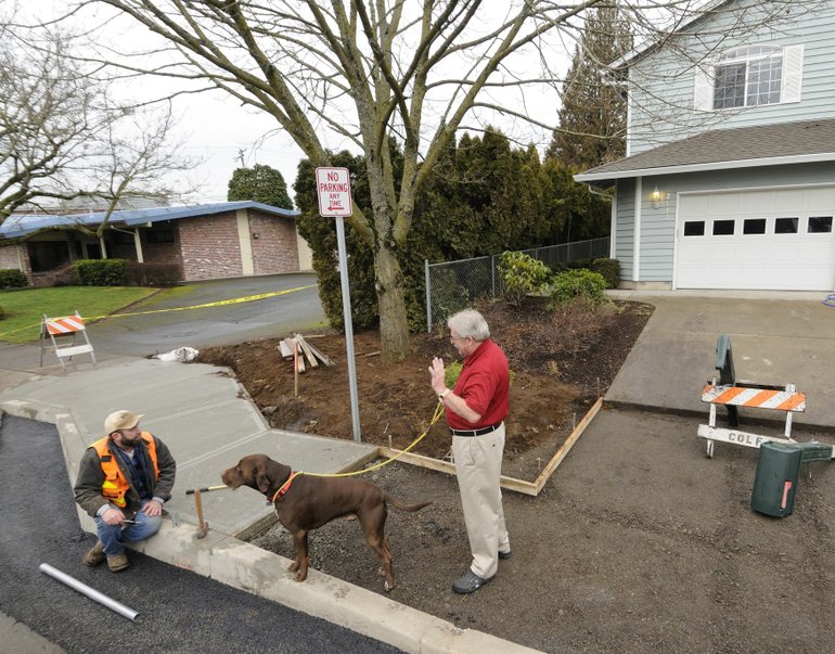 Chris Peterson, with his dog, George, talks with Dallas Browning of Colf Construction during recent sidewalk construction on East McLoughlin Boulevard.