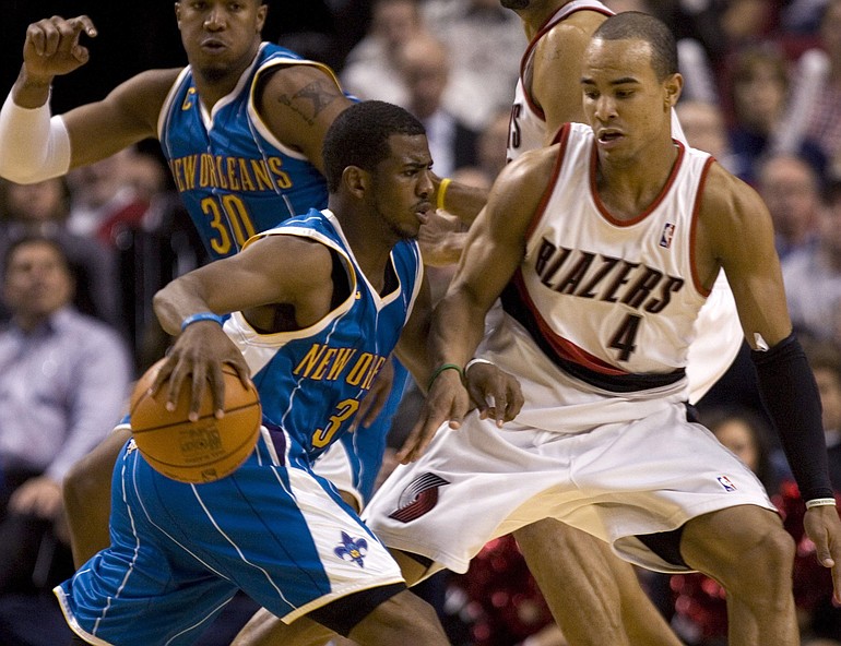 New Orleans Hornets guard Chris Paul, left, drives on Portland Trail Blazers guard Jerryd Bayless during the second half of their NBA basketball game in Portland, Ore., Monday, Jan. 25, 2010. Paul scored 24 points and sank the game winning basket to beat the Blazers 98-97. In the background are Hornets forward David West, left, and Blazers center Juwan Howard.