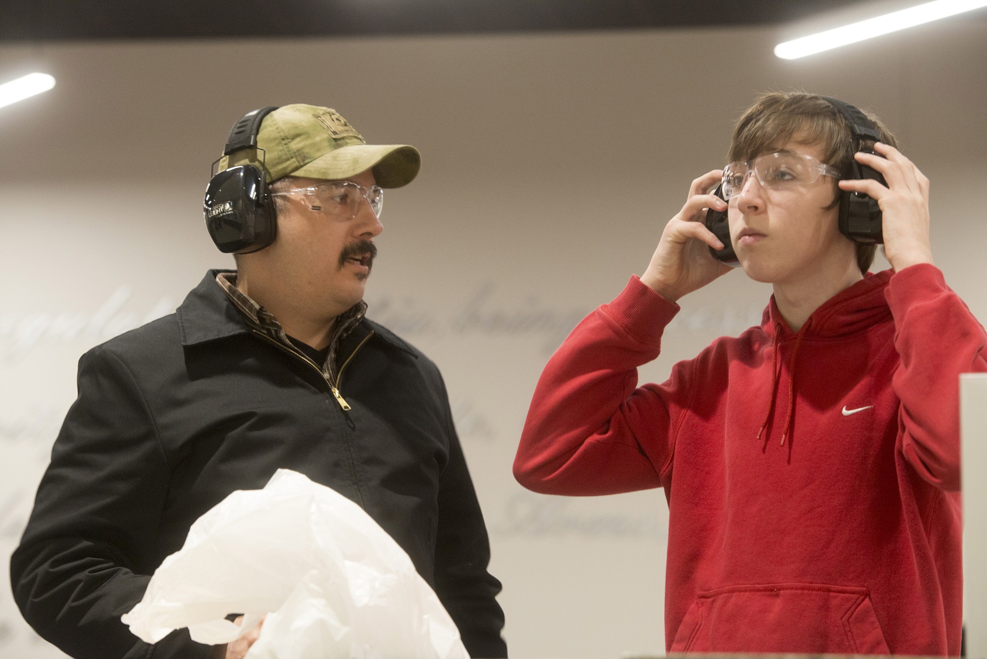 Joaquin Legorreta and his son, Elijah Legorreta, 14, put on their safety goggles and ear protection before they take turns firing at targets at Elite Shooting Sports in Manassas, Va.