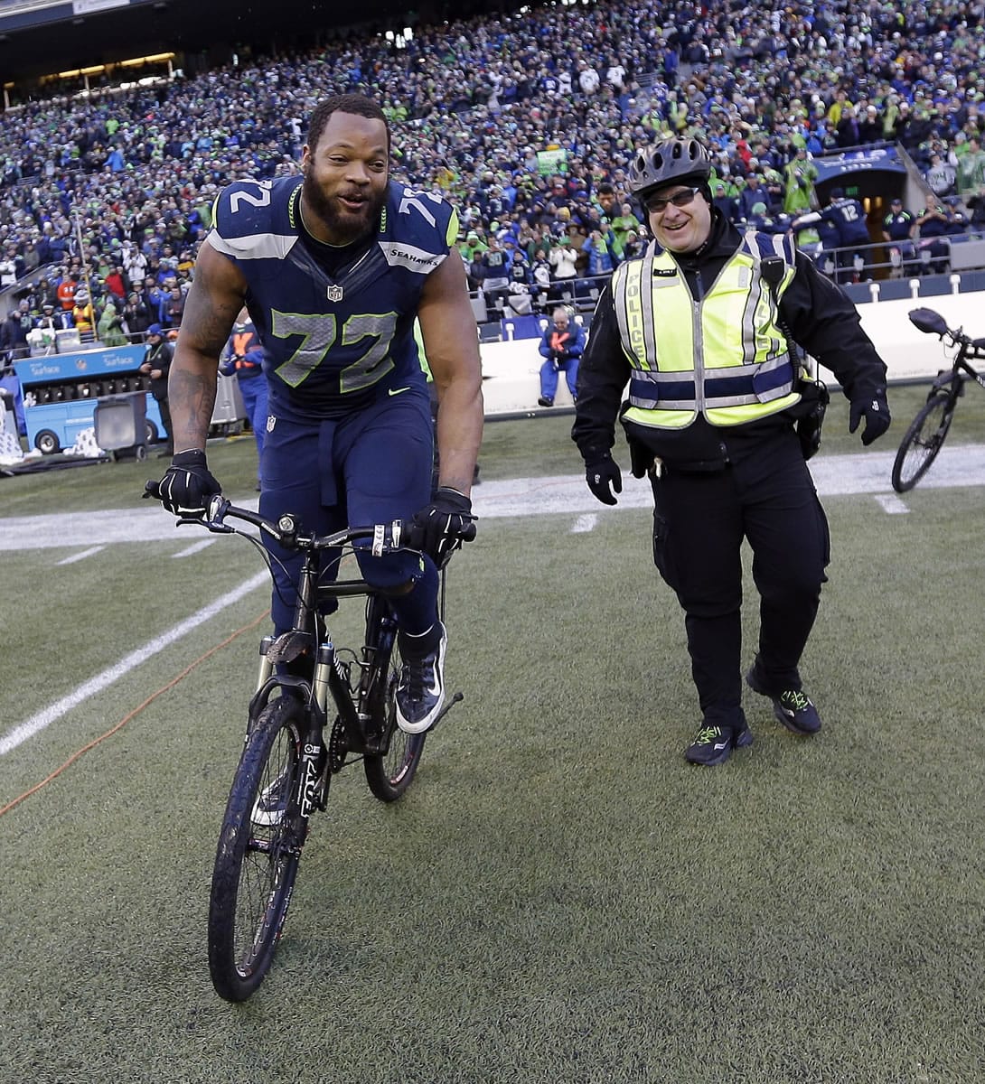 Seattle's Michael Bennett borrows a police officers bike for a celebration lap around CenturyLink Field after winning the NFC Championship game against the Green Bay Packers.