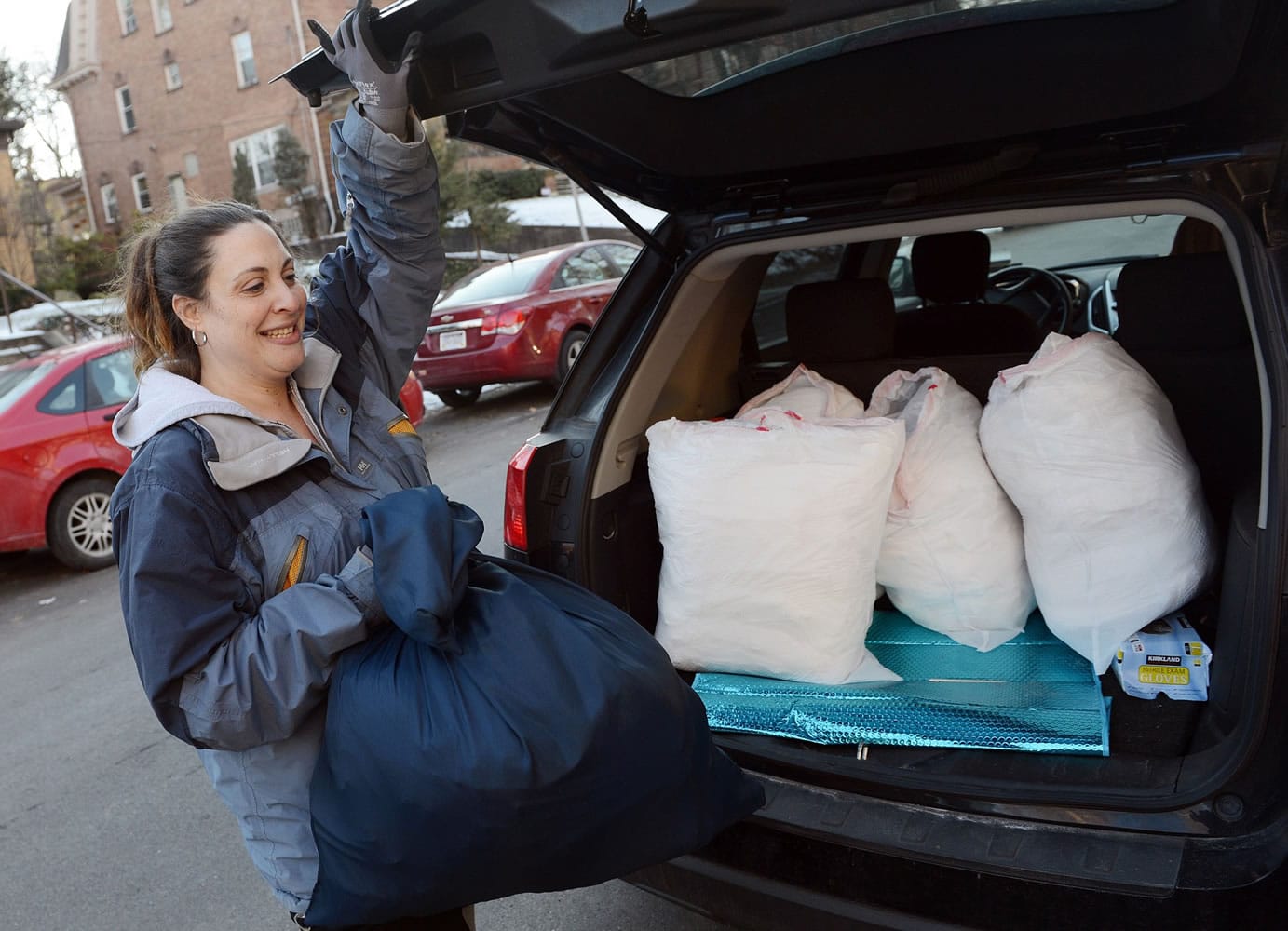 Ilene Scoratow pulls a bag of clean laundry from her vehicle while making a drop-off at Weinberg Terrace on Jan. 15 in Squirrel Hill, Pa.