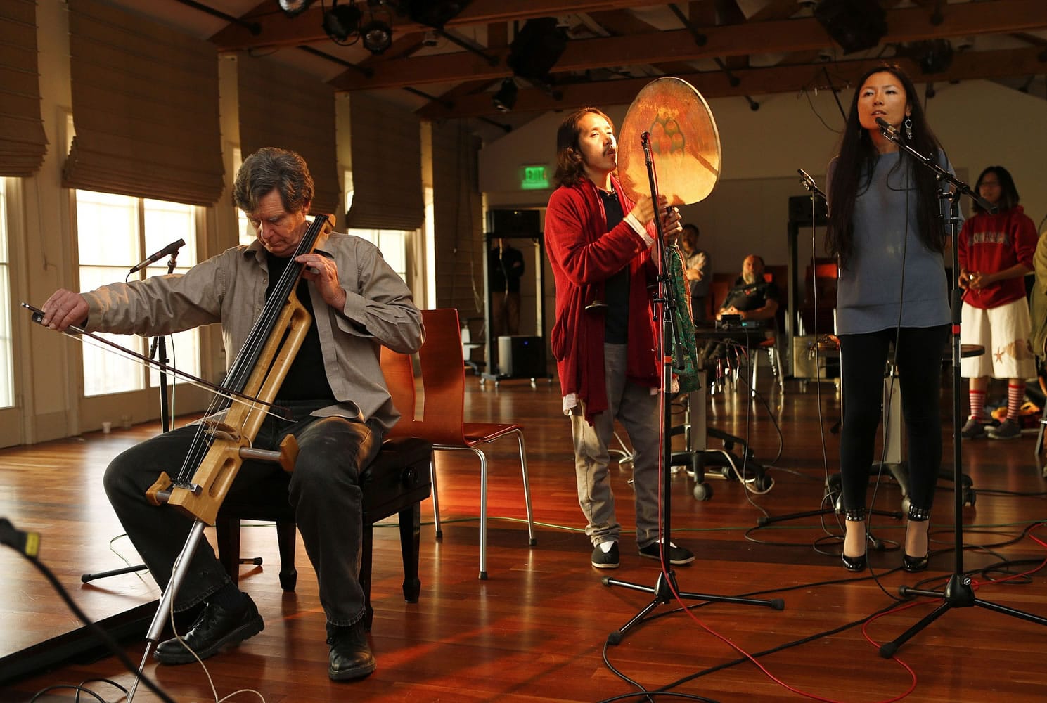 Chris Chafe, left, director of the Center for Computer Research in Music and Acoustics at Stanford University, plays his handmade electric cello with singers Reshi Tsering Tan, center, and Cecilia Wu, right, along with musicians in Virginia Tech and Santa Barbara via the Internet in Stanford, Calif.