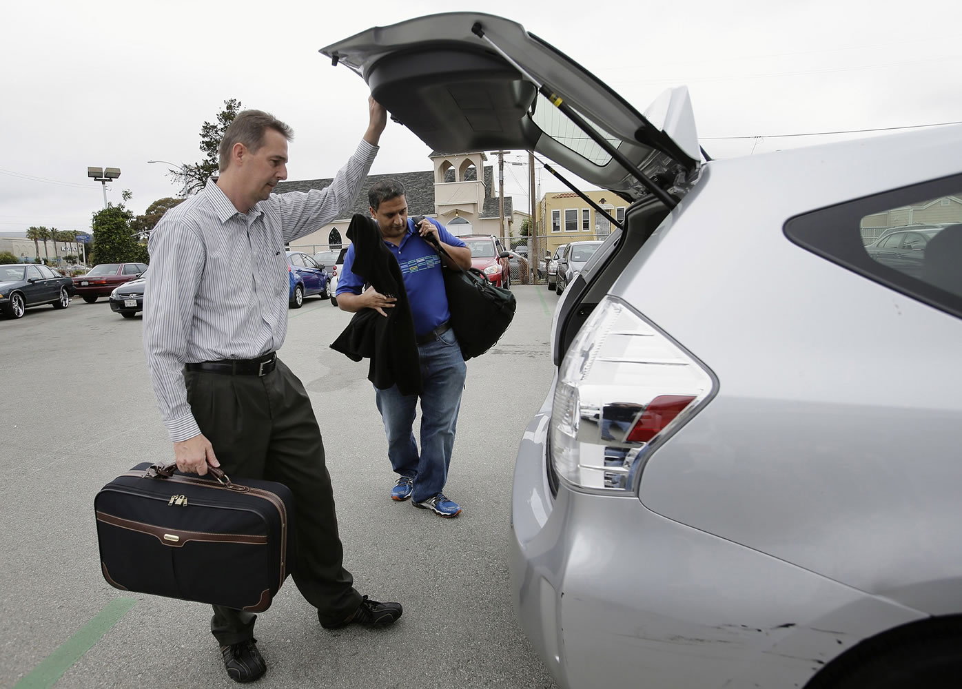 Gary Reyes/Bay Area News Group
John Penny, left, and Marty Puranik load their luggage into a rental Prius at FlightCar in Millbrae, Calif. FlightCar is a car-sharing service that allows travelers to leave their cars in a parking lot so that others can rent them while they are gone.