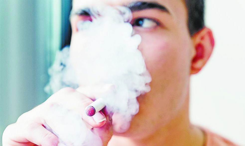 A young man uses an e-cigarette.