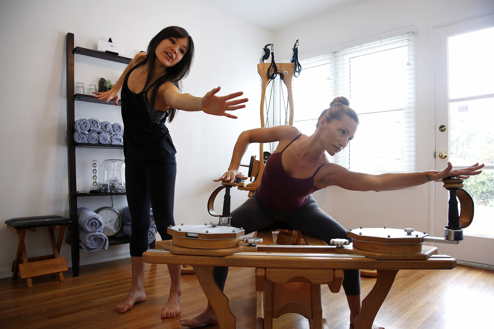 Deandra Lee, left, demonstrates the movement client Danielle Thulin should be doing on the Gyrotonic Tower Machine in Los Angeles.