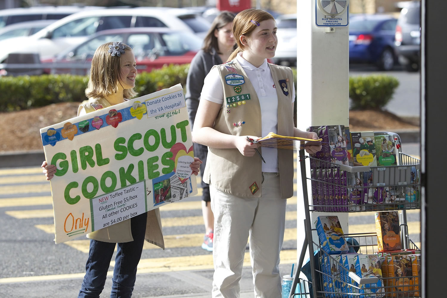 Amy Rapp, left, and Maddy Surface, members of Girl Scout Troop 42561, sell boxes of Girl Scout Cookies on Sunday outside the Fred Meyer in Salmon Creek. Rapp has sold about 150 cookies so far this season, while Surface has sold nearly 900.