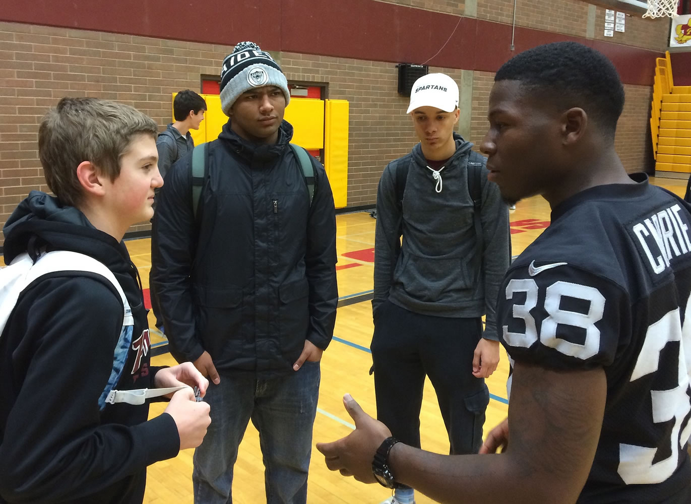 Oakland Raiders cornerback T.J. Carrie talks to Prairie High School students Dante Heithschmidt (left), Adam Ayala (Raiders hat) and Rashaan Bohanan on Tuesday.