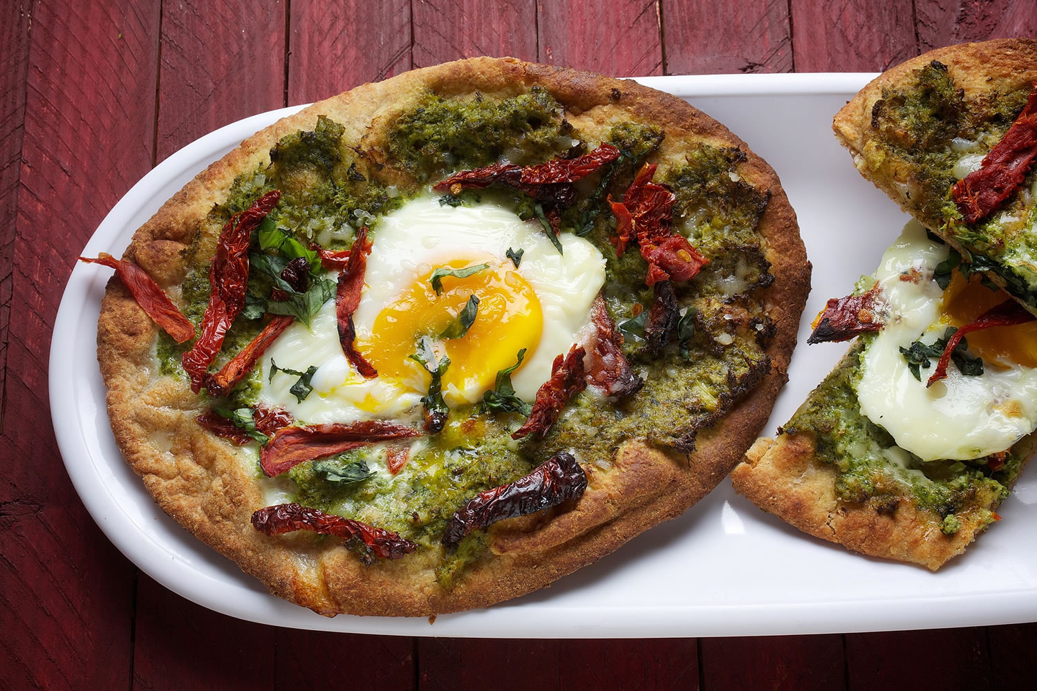 Broccoli pesto is used as the base a flatbread pizza that also features sun-dried tomatoes and an egg cooked to runny perfection.