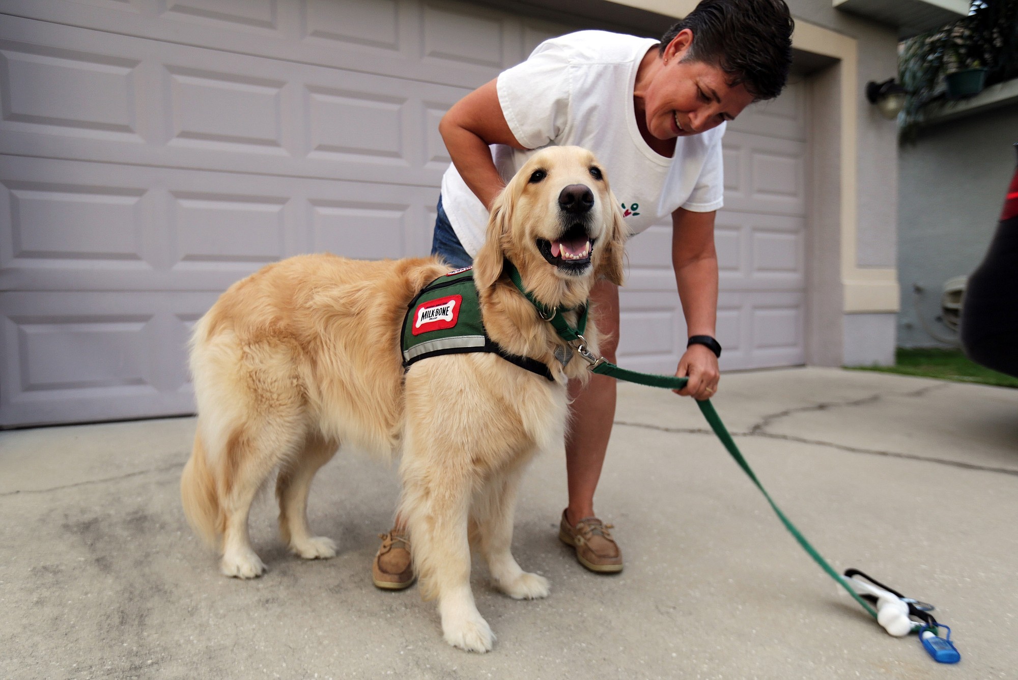 Lori Eagen commends her service dog, Tober, outside their home in Kissimmee, Fla., lat month. Tober, a golden retriever, can tell when Lori is about to have a seizure, and find her family members, and alert them.