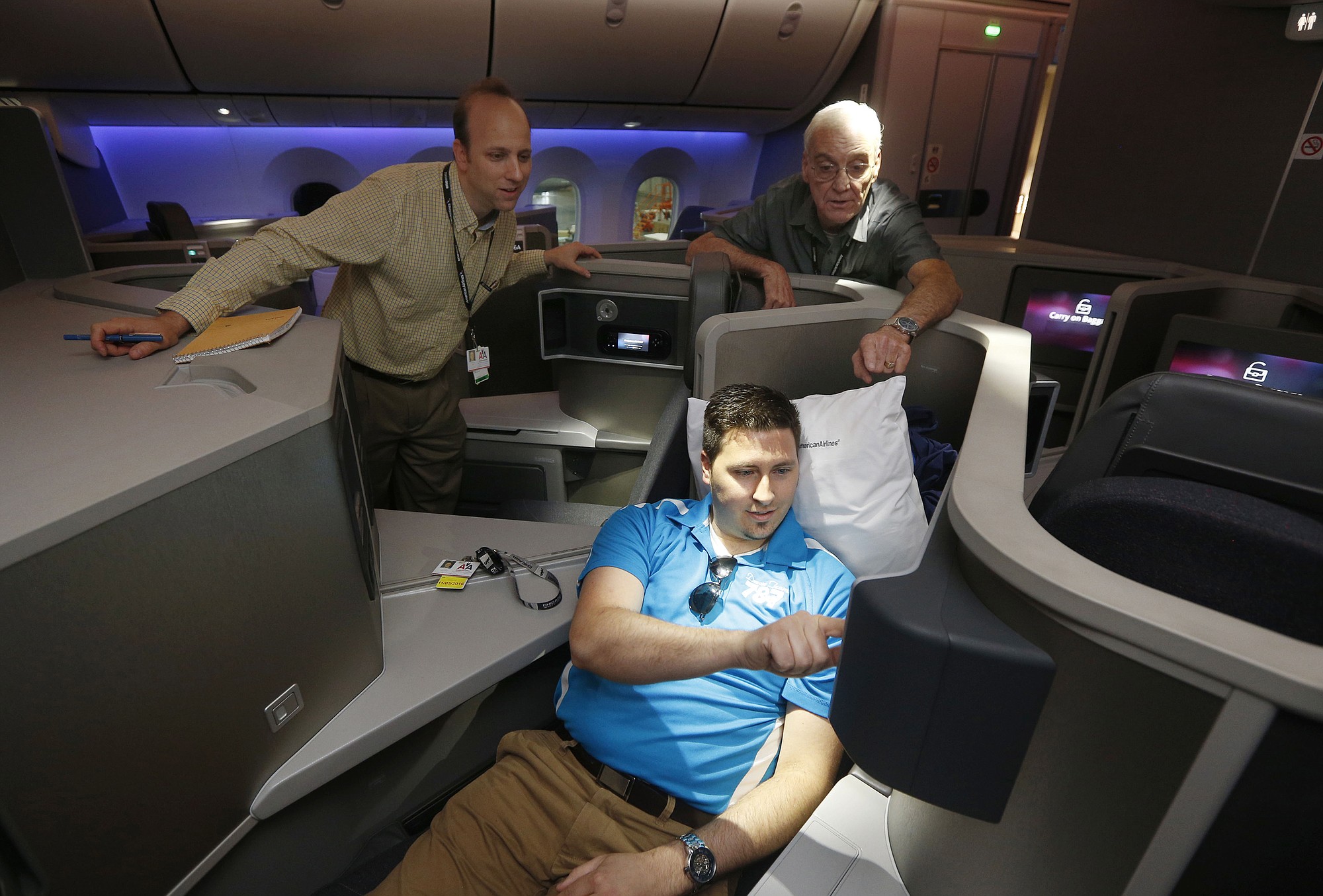 American Airlines employees Steve Kmetz, from left, Frank Hettlinger and Norm Rainwater look at in-flight entertainment in the business class section during a media tour of a Boeing 787.