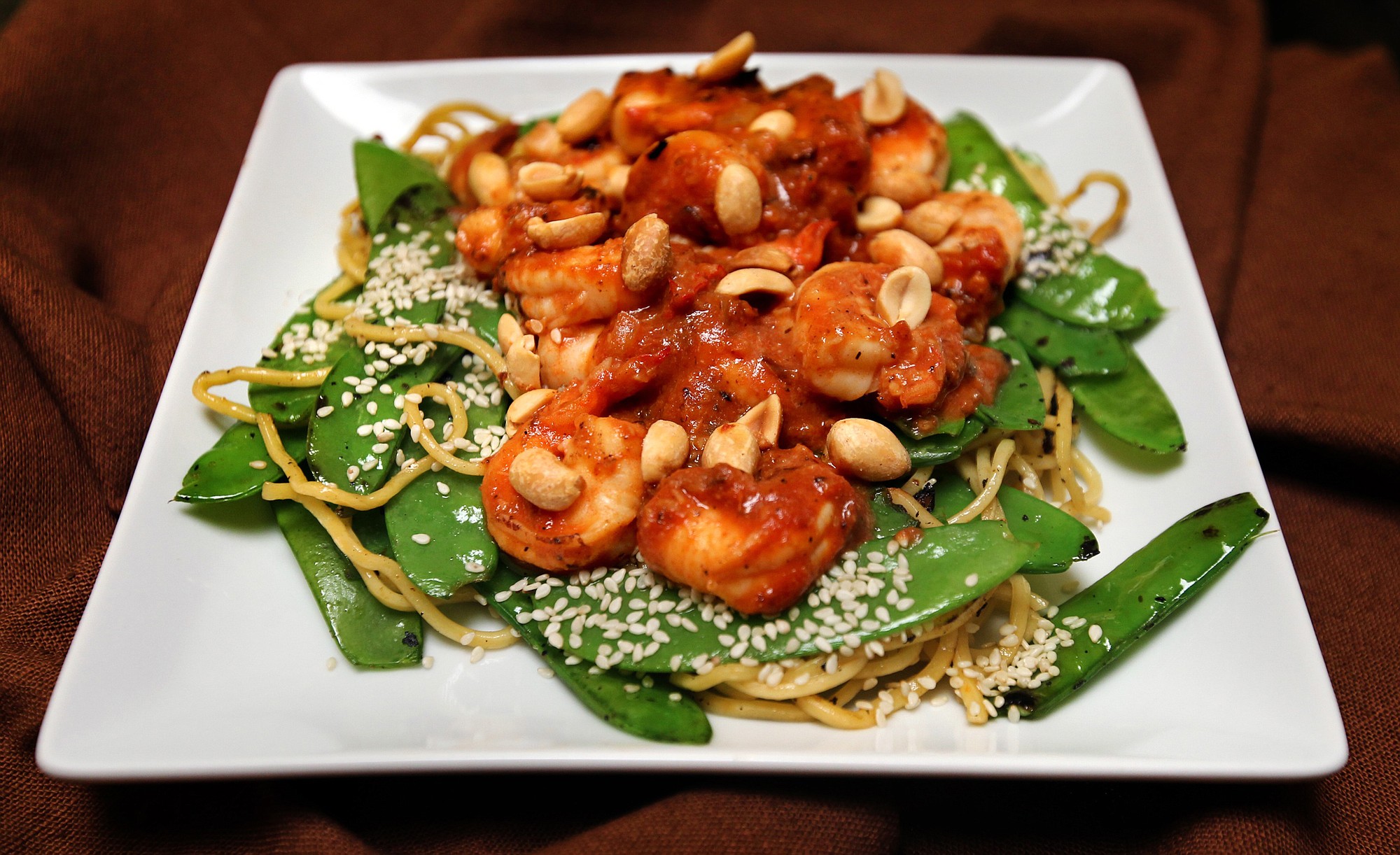 Stir-fried shrimp are served with snow peas and sesame noodles for a spicy dinner that's fast and easy.