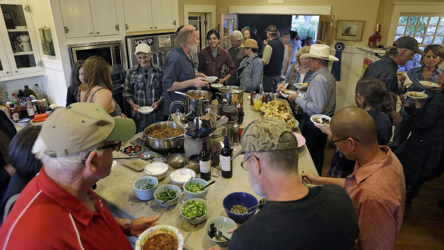 Attendees gather in the kitchen while chili is served after the &quot;Deep End Sessions&quot; concert at David Bunn's ranch house on May 24 in Santa Paula, Calif.