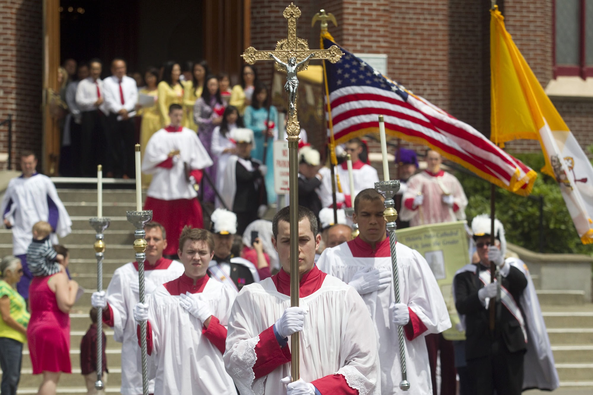 An altar server emerges, carrying a cross, from the Proto-Cathedral of St. James the Greater on Sunday.