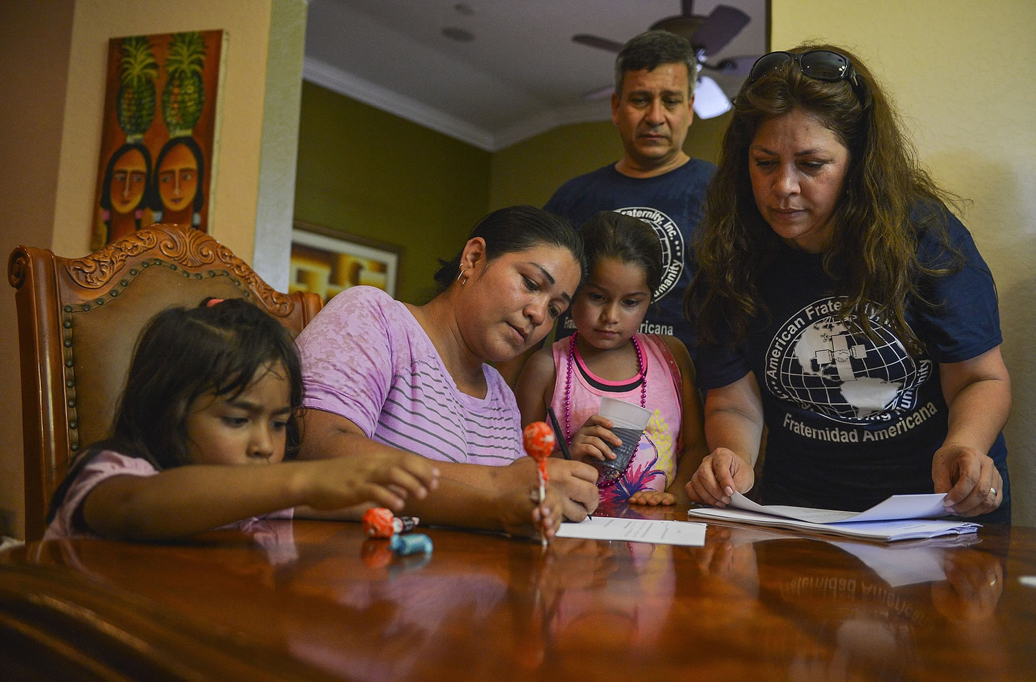 Claudia Fonseca, center, flanked by her children Yardley Vanegas, 5, left, and Shirley Vanegas, 8, signs over guardianship of the youths to Nora Sandigo, right, on June 7 in Miami, as Sandigou2019s husband, Reymundo, looks on.