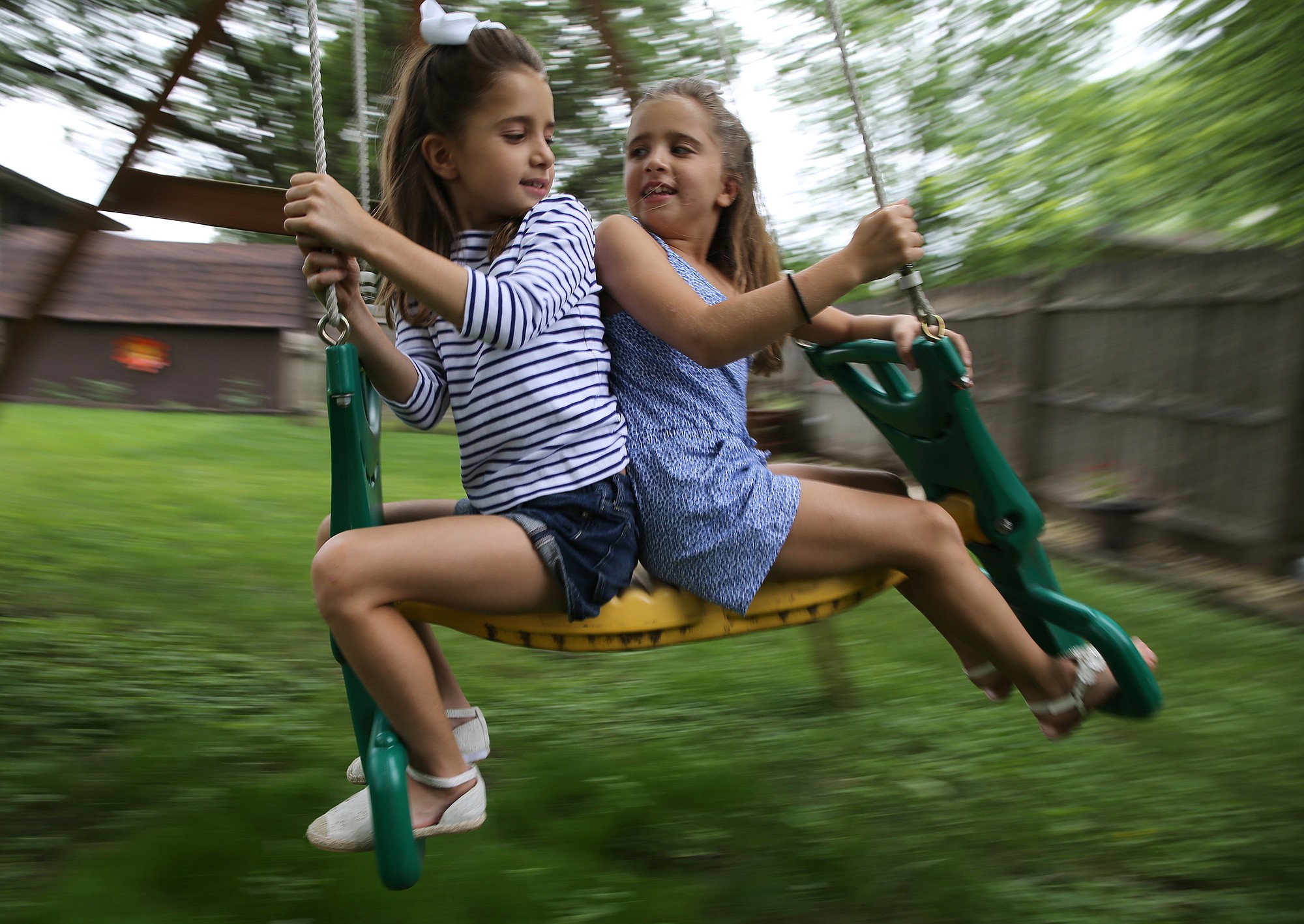 Sophia Moreno, who suffers from allergies and asthma, left, and her twin sister, Isabella, play together in the backyard of their home on June 25 in Shorewood, Ill.
