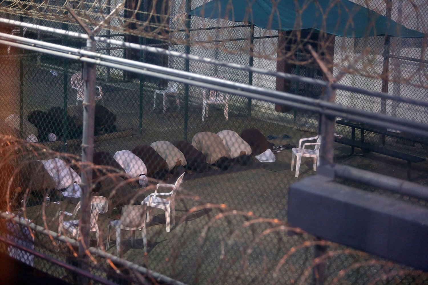 War-on-terror captives from two different cellblocks, separated by a fence, conduct communal evening prayers at the Camp 6 prison building for cooperative captives at the U.S. Navy Base at Guantanamo Bay, Cuba, on July 7. This photo was taken through a closed window. U.S.