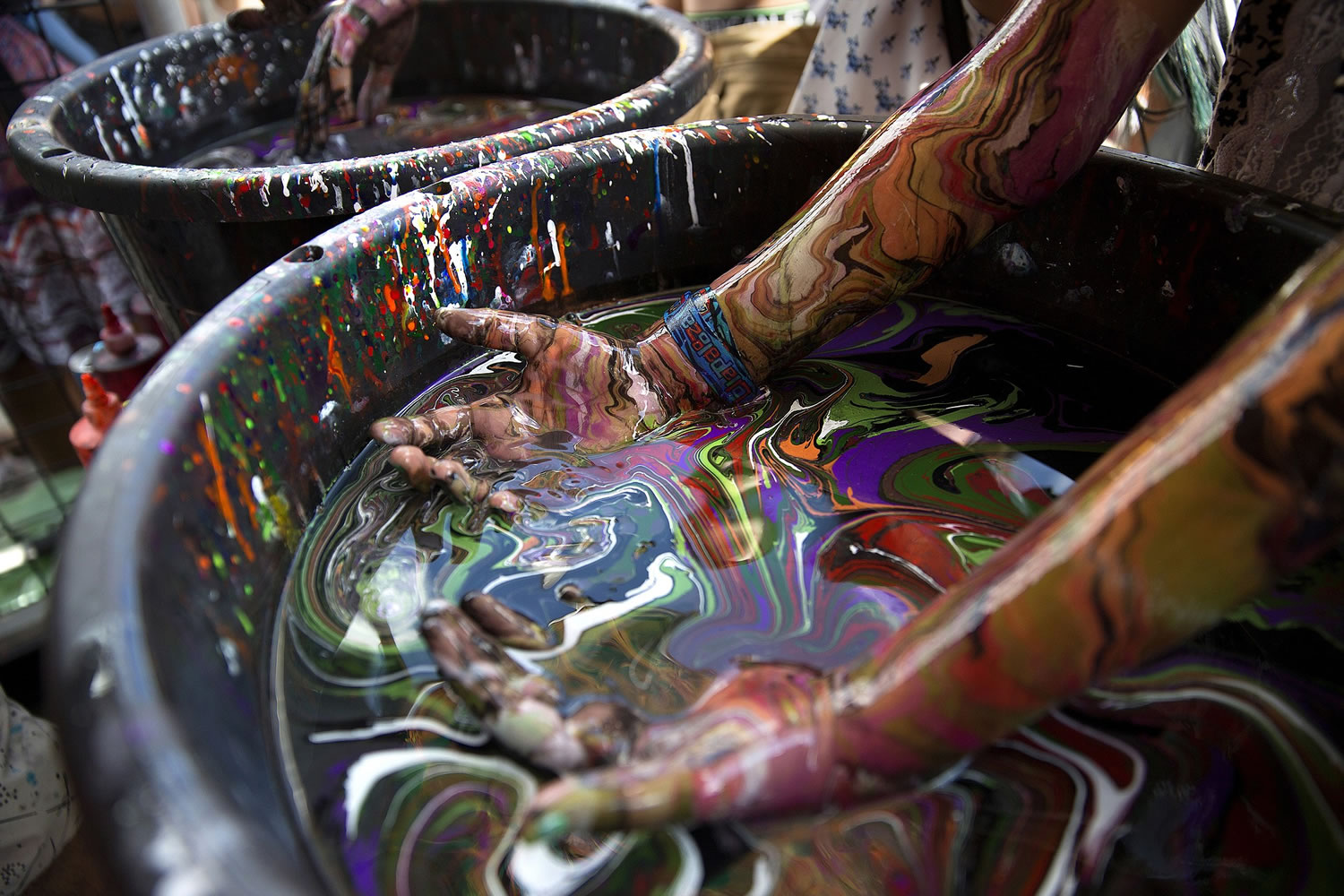 People tie-dye their arms in large barrels Saturday at Lollapalooza Music Festival in Grant Park in Chicago.