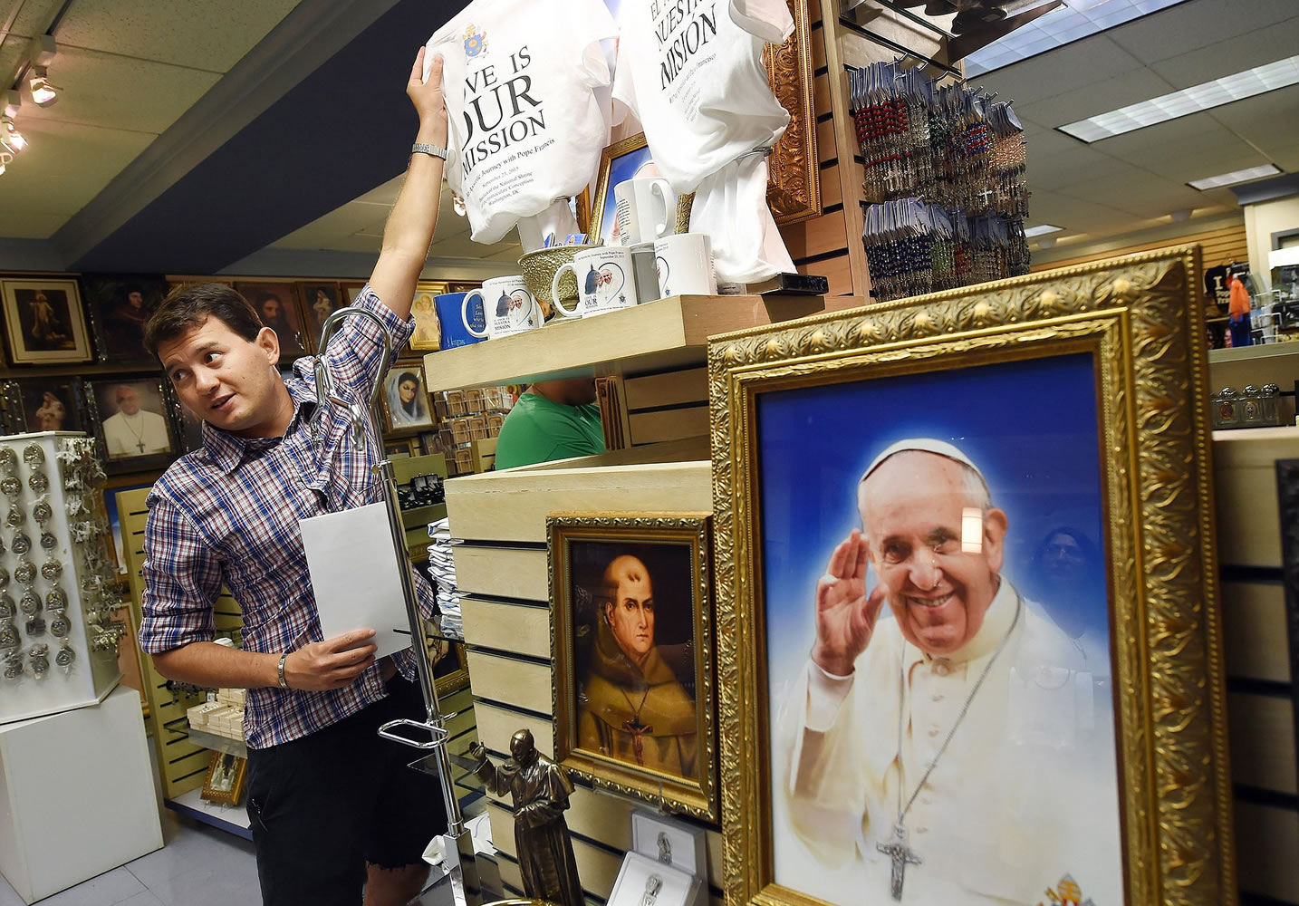 Carlos Limongi takes a shirt from a display of Pope Francis-related items at the gift shop within the Basilica of the National Shrine of the Immaculate Conception in Washington, D.C.