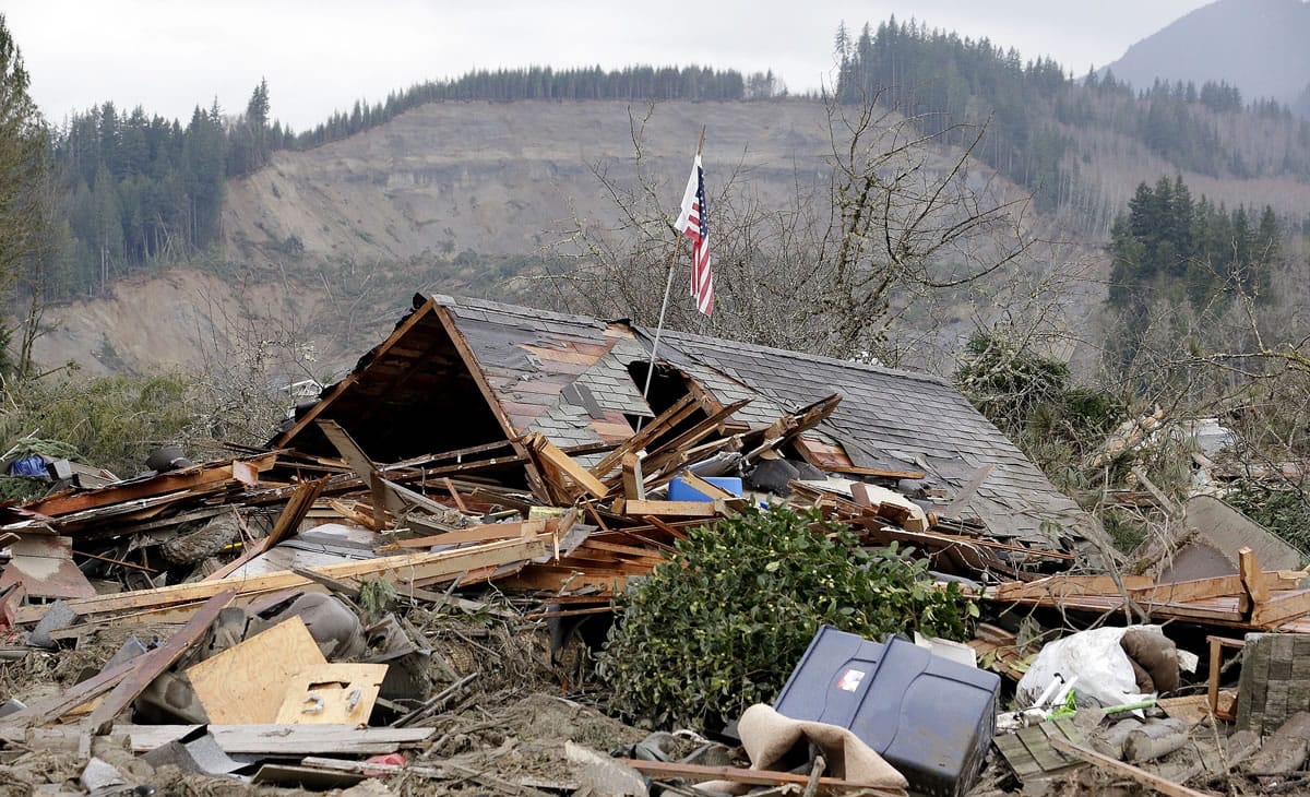 A flag stands March 25, 2014, in a demolished home in the debris of a deadly mudslide from the hill behind that happened several days earlier in Oso.
