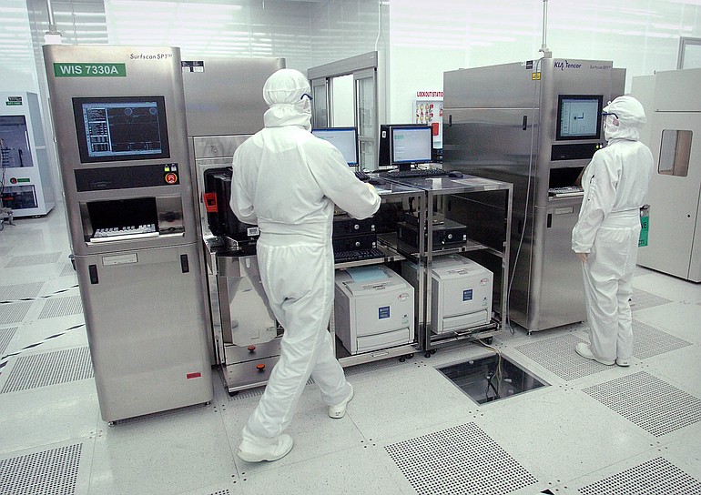 SEH America employees work on a silicon wafer manufacturing machine in the company's Vancouver plant.