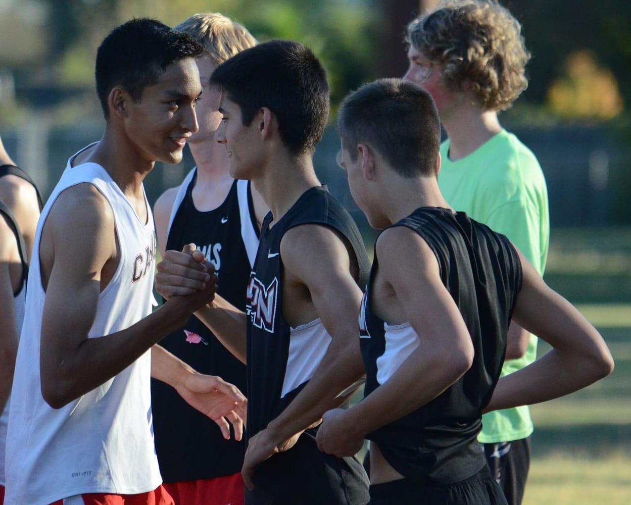Camas runner Said Guermali, left, greets members of the Union cross country team before a race Tuesday at Pacific Park.