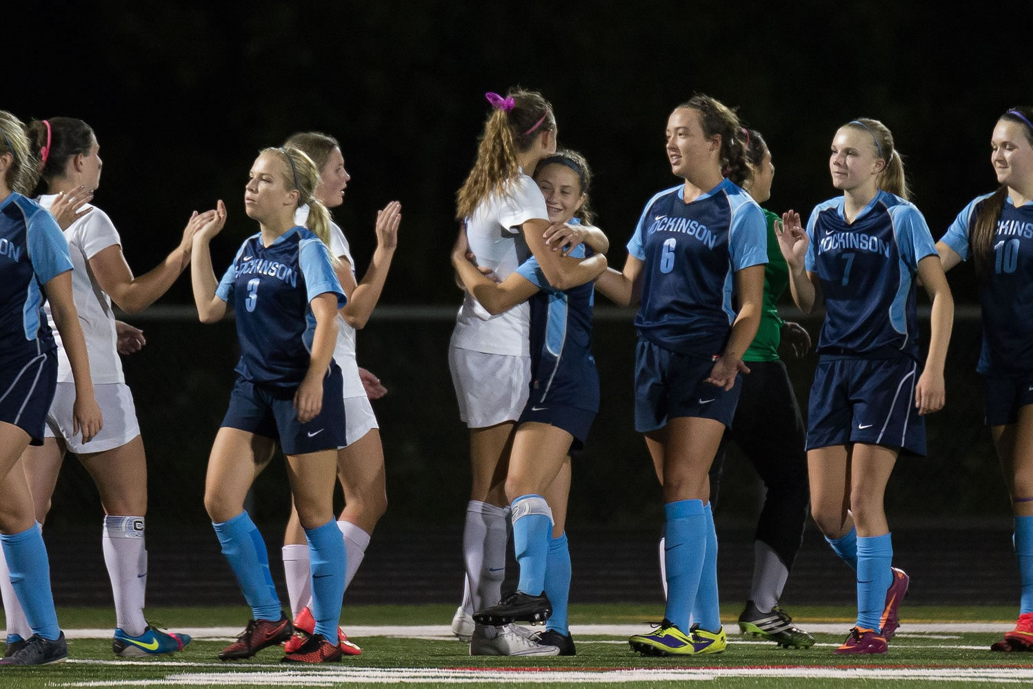 Ridgefield's Taryn Ries (center, in white) gives a post-game hug to Hockinson's Rylee Seekins after the Spudders' overtime win against the Hawks last week.