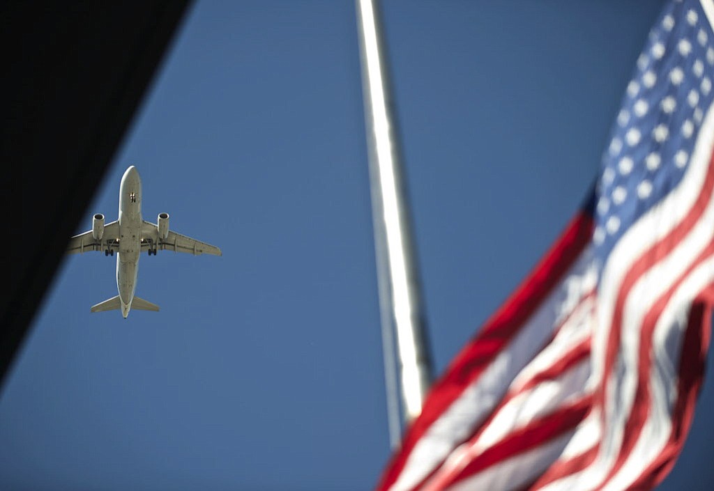 A plane passes overhead as the American flag is raised Sept.
