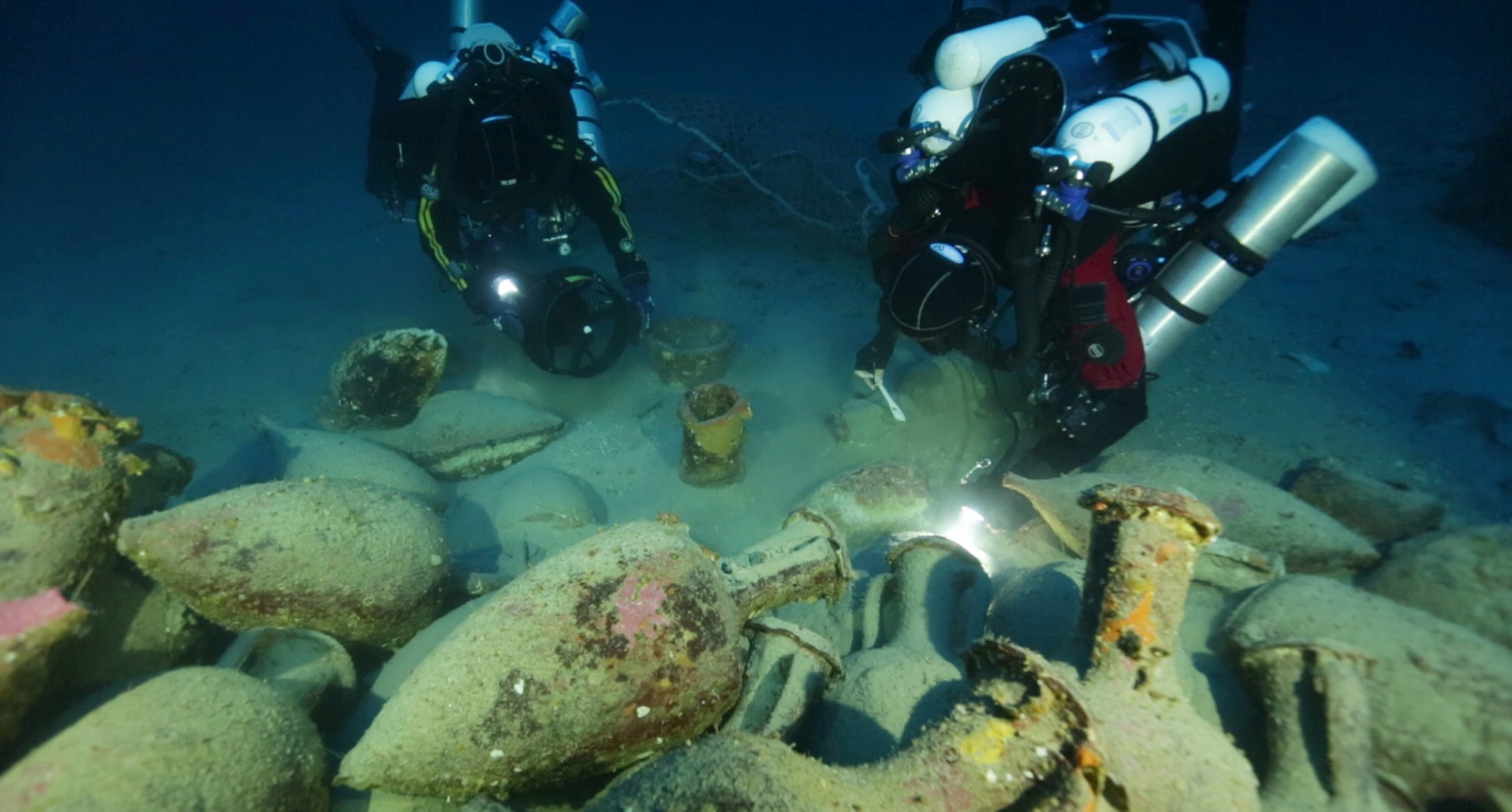 In this undated photograph provided by Global Underwater Explorers, divers illuminate Greco-Roman artifacts from a ship that sank during the Punic Wars between 218-201 B.C., in the Mediterranean Sea, off the Aeolian Island of Panarea.