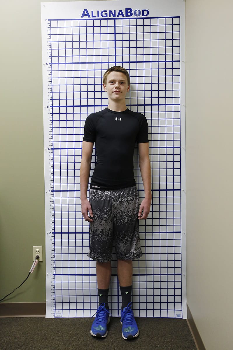 Trevor Johnson, 15, stands in front of a grid for evaluation of his scoliosis Oct. 6, 2014 at Empower Physical Therapy in Exton, Pa. Lisa Angioli, a physical therapist at Empower Physical Therapy, uses the Soliosis Schroth method with Johnson. (Michael S.