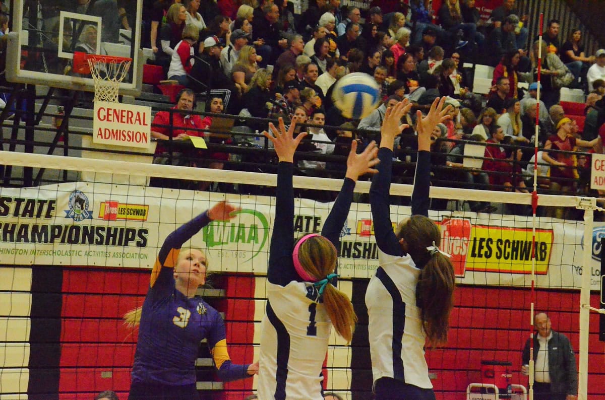 Columbia River's Andrea Demlow (3) hits the ball over Auburn Riverside's blockers during the first set of a Class 3A state semifinal match Saturday in Lacey.