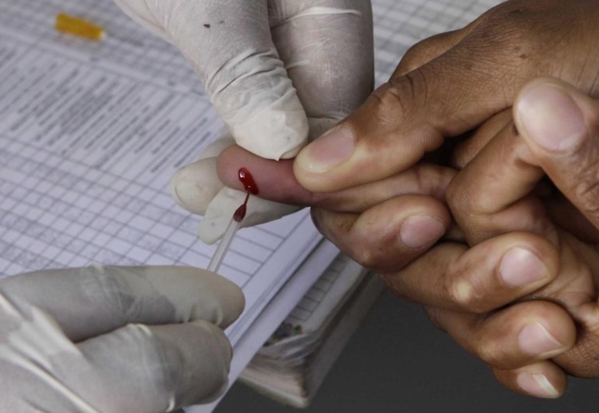 A patient undergoes a pin prick blood test inside a health care clinic.