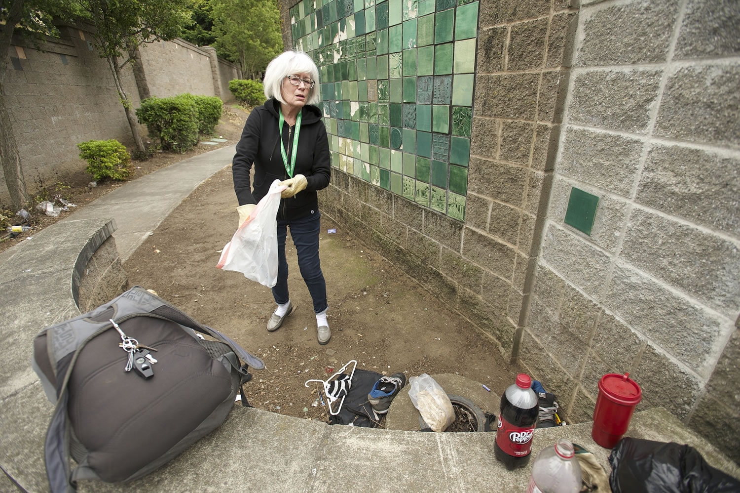 Photos by Steven Lane/The Columbian
Hough neighborhood resident Nancy Schultz, picking up trash in the Mill Plain Boulevard sound wall's alcoves in mid-May, would like to ensure the 2001 community tile art project on the walls are preserved if the alcoves are blocked off or torn down.