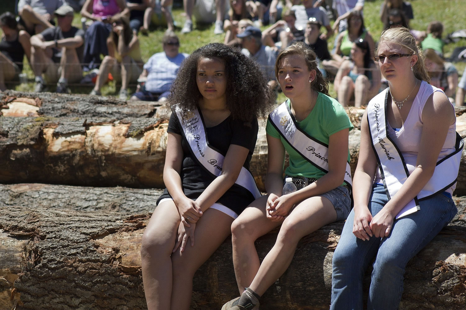 Princesses Brandi Stokes, 14, from left, Sierra Joner, 14, and Mariah Goff, 14, sit on logs as they watch the Amboy Logging Show on Saturday.