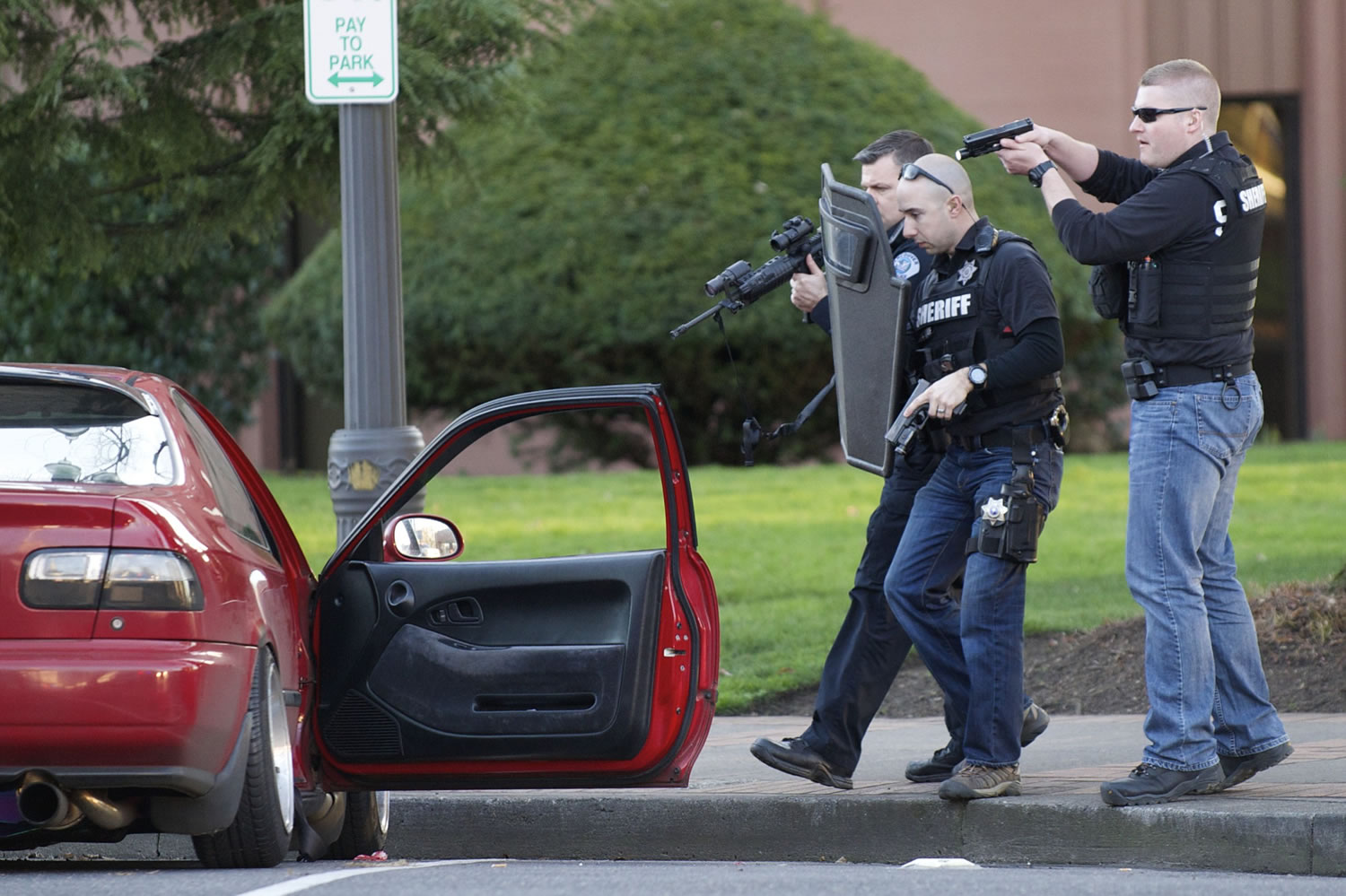Police carefully approach a red car parked in front of the Clark County Courthouse on Friday afternoon.