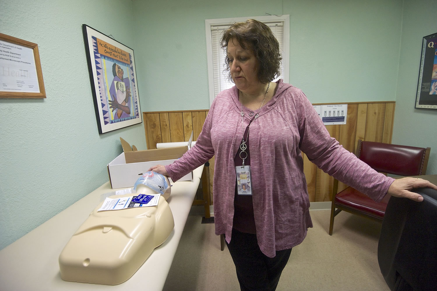 Clark County Public Health educator Sandi Kendrick looks down at a dummy used to demonstrate how to administer lifesaving measures given to clients in rescue kits, at the Harm Reduction Center.