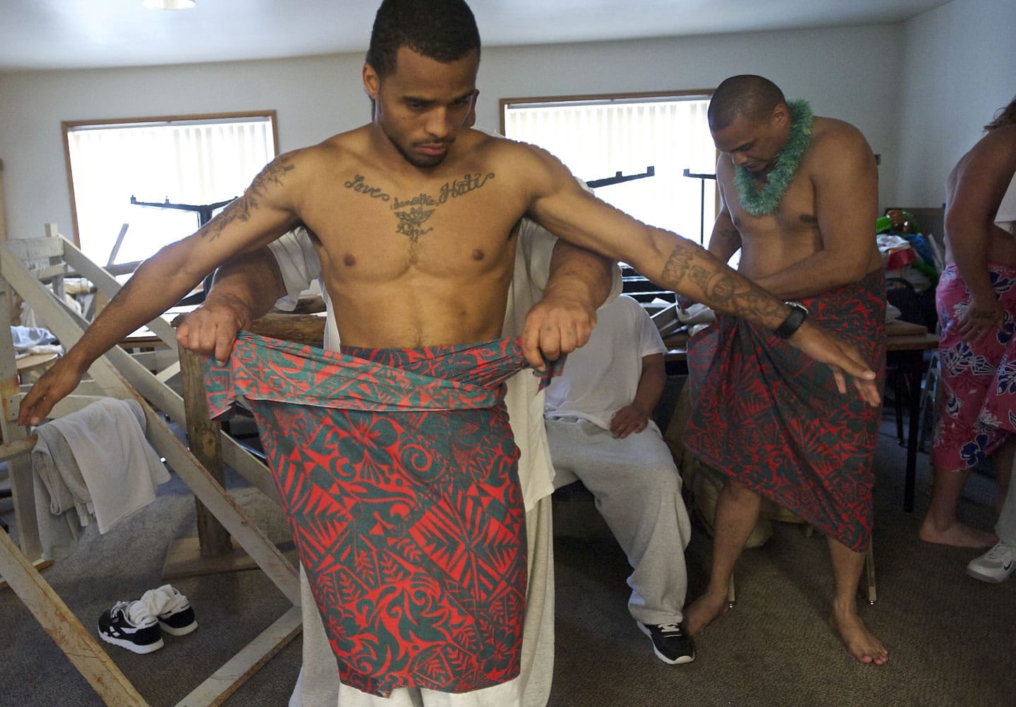 Offender Robert Baker gets help putting on his sarong before a dress rehearsal.