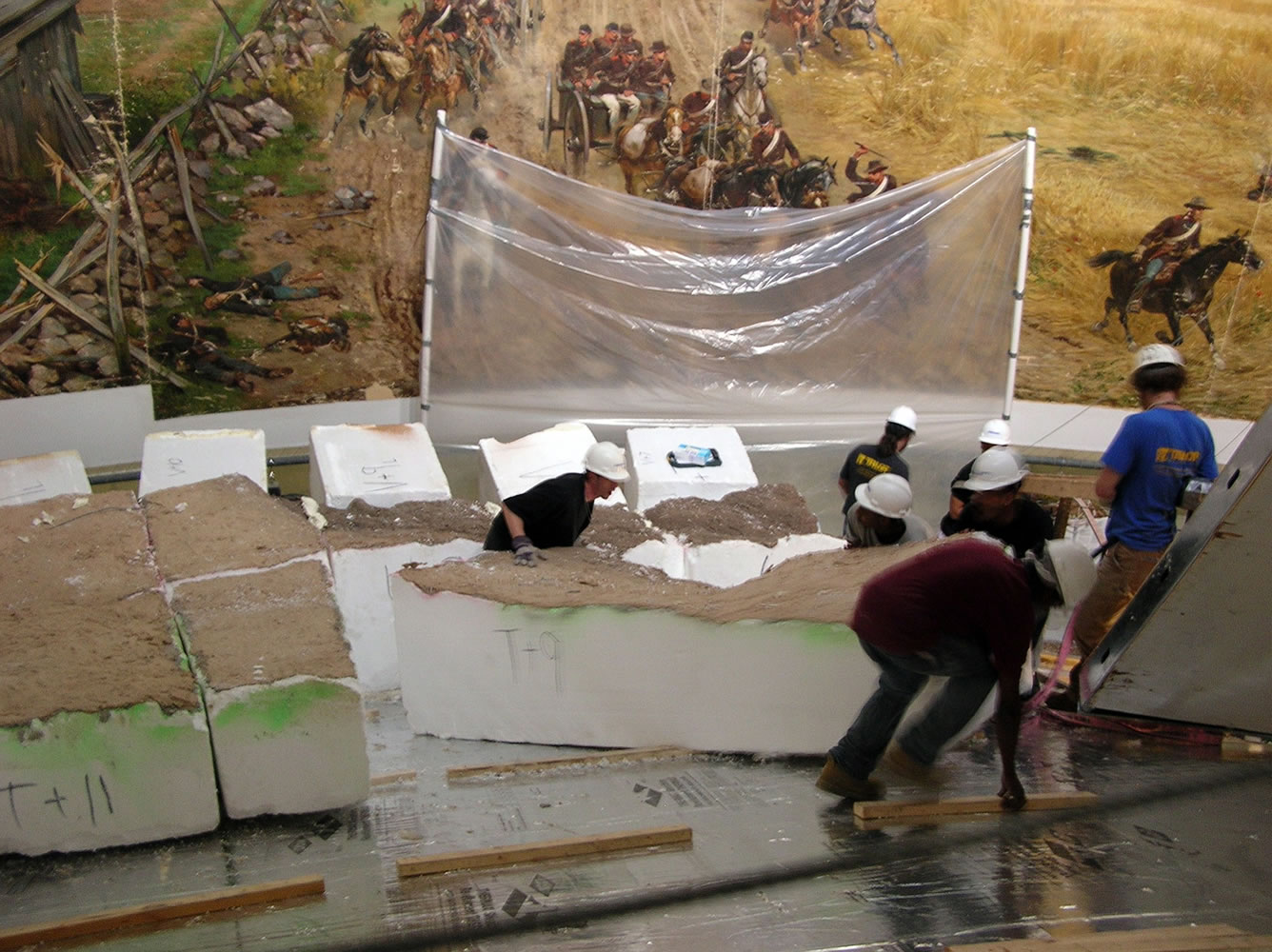 A crew moves pieces of the diorama, which provide a 3-D effect, in front of the cyclorama painting.