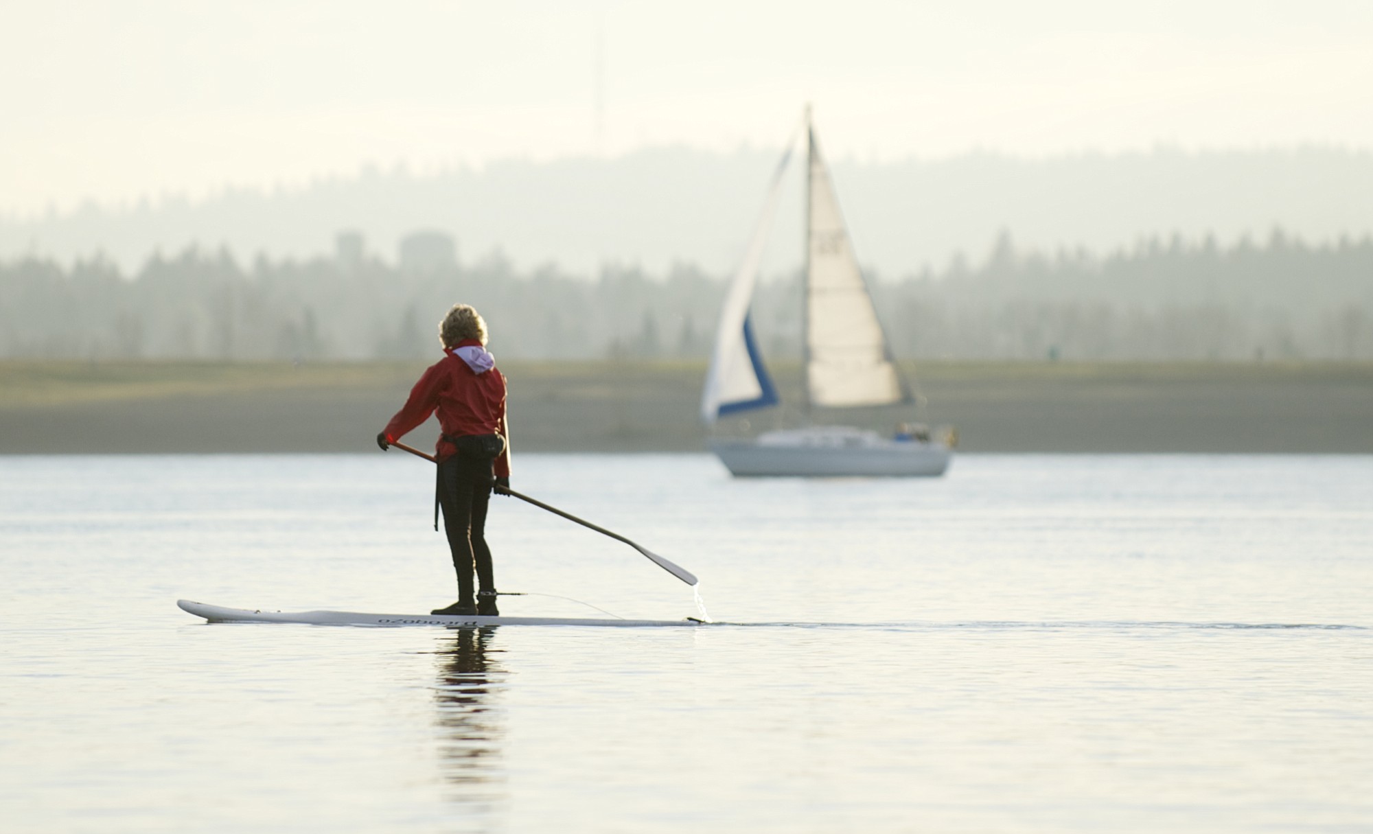 A paddle boarder and a sailor take advantage of a beautiful day on the Columbia River near Wintler Park, Tuesday, January 20, 2015.