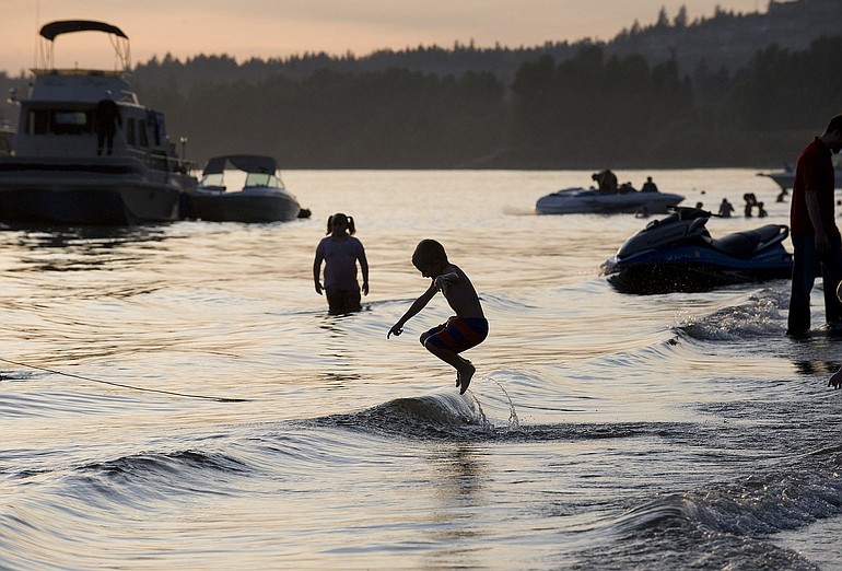 Children splash in the water and people enjoy the sunset from their boats as they await the Fourth of July fireworks show at Cottonwood Beach in Washougal. The once-neglected beach was transformed into Capt.