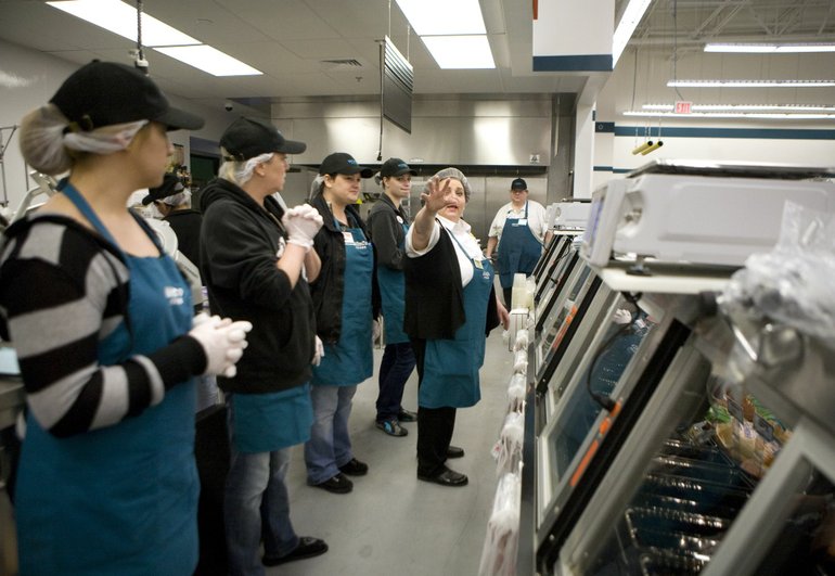 Bonnie Thompson, with outreached arm, trains employees in the deli at the new WinCo Foods store.